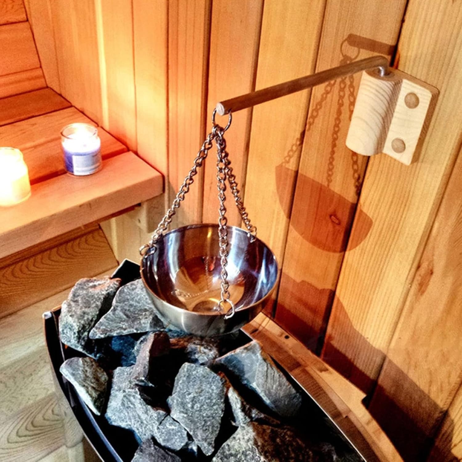 Stainless steel sauna aroma cup hanging above hot stones inside a cedar sauna