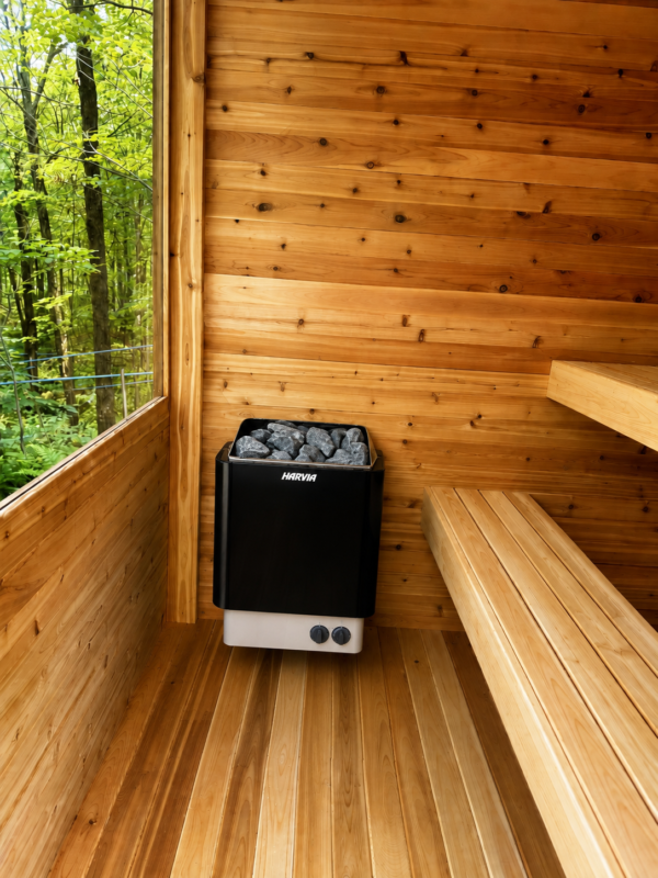 Moderna Cedar Sauna Interior with Harvia Electric Heater | SaunaSpa Interior of a Moderna cedar sauna featuring a wall-mounted Harvia electric sauna heater, wooden benches, and a large window overlooking the forest.